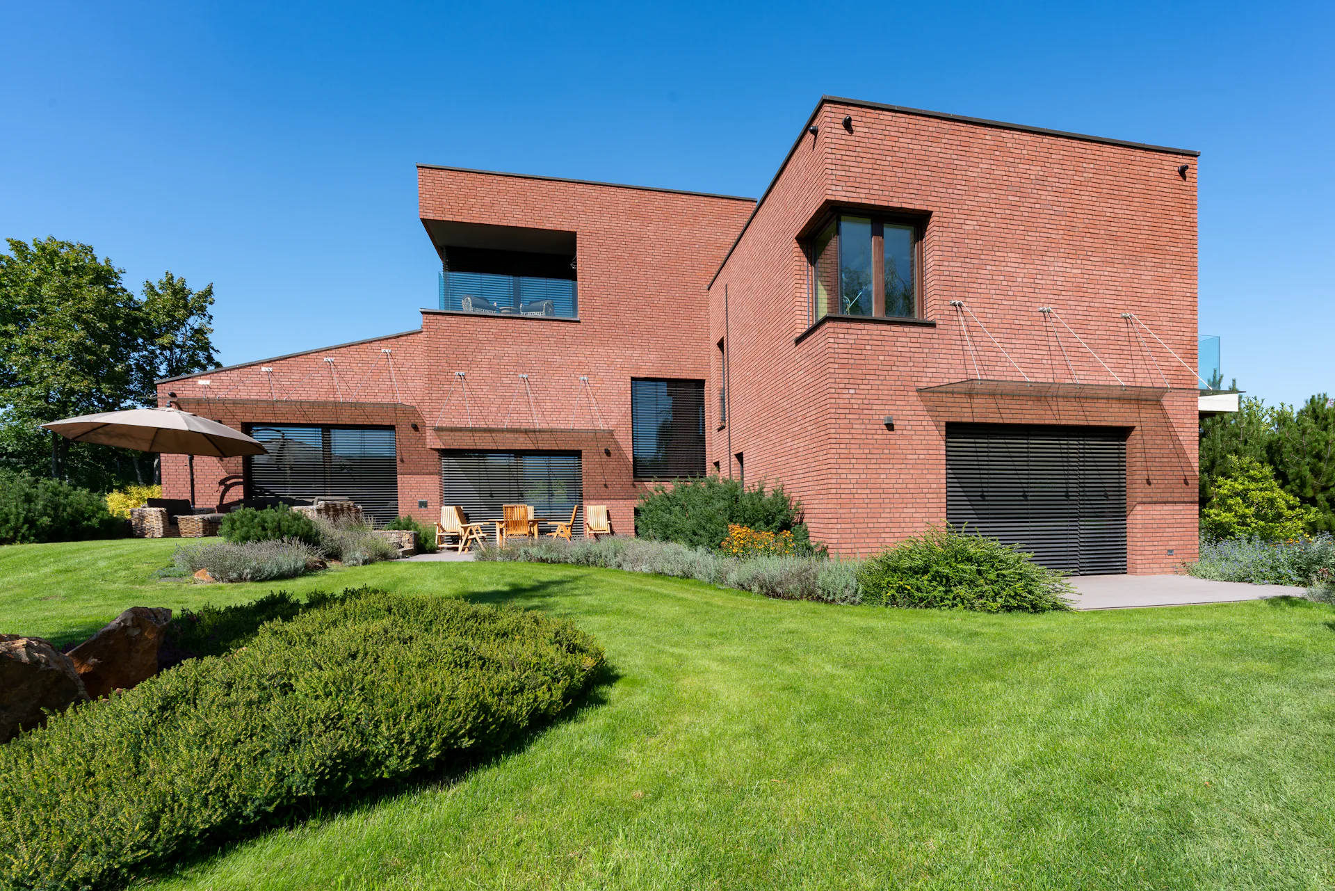 Contemporary brick family home with large windows and a landscaped lawn